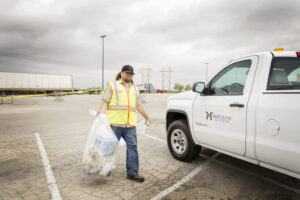 More Clean of Texas employee in high visibility vest carrying a bag of trash to company truck