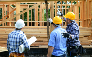 Three construction workers in hard hats and work shirts inspecting a construction site